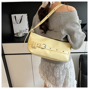 Rear view of a model wearing the light yellow glossy underarm bag with metal buckle strap