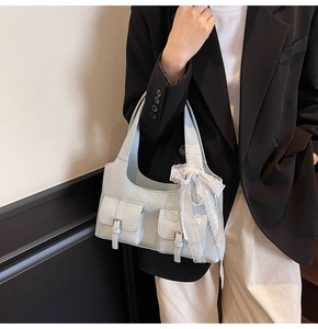 Dettaglio borsa Hobo celeste con fiocco di pizzo e tasche su un blazer nero elegante