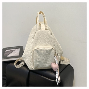 Détail du sac à dos plissé blanc crème avec pendentif coeur et poche avant zippée