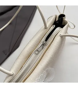 Détail de la fermeture éclair argentée et texture du cuir PU beige avec nœud en soie