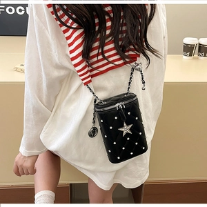 Detail of black quilted cylindrical crossbody bag with silver rhinestone star and chain strap