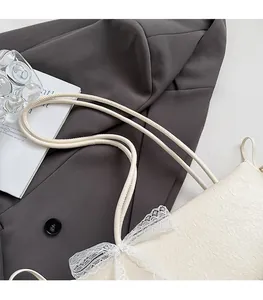 Détails de la texture gaufrée et des finitions en dentelle du sac à bandoulière crème
