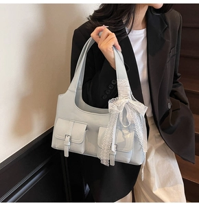 Dettaglio borsa sottobraccio azzurra lucida con tasche esterne e fiocco di pizzo bianco