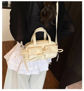 Détail du sac bandoulière blanc crème avec nœuds décoratifs et poches avant