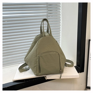 Gros plan d'un sac à dos triangulaire en nylon vert Morandi avec poche zippée et poignée
