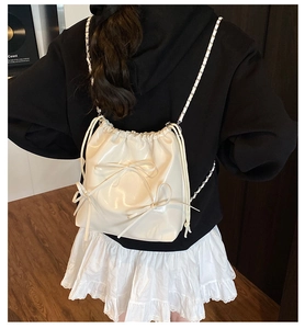 Detail of silver bow on glossy white drawstring backpack with metal chain strap
