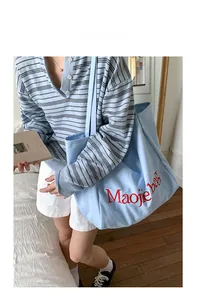 Détail de la broderie rouge sur le sac cabas en toile bleu clair avec bandoulières