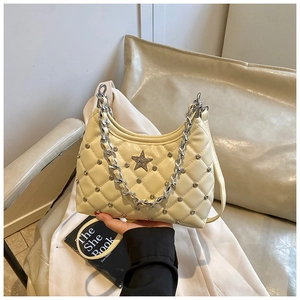 Close-up of quilted cream handbag with silver studs, star diamond and chain handle