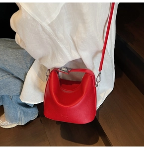 Model wearing a red lychee pattern bucket bag with silver hardware on a wooden stairs background