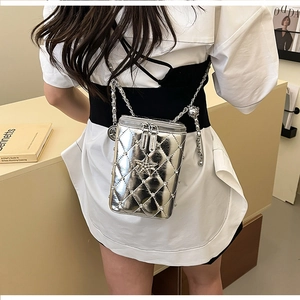 Detail of silver quilted crossbody bag with star pendant and woven chain strap