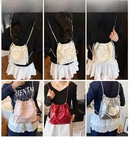 Detail of a shiny silver bow-knot drawstring backpack with chain straps in several colors