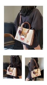 Detail of white leather tote bag featuring a cartoon bear print and decorative silk scarf handle