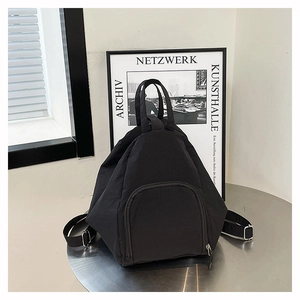 Sac à dos triangulaire minimaliste en nylon noir sur une table en métal avec bandoulières