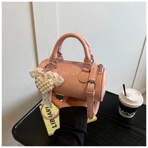 Pink cylinder handbag with lace bow and pearl heart charm detail on pleated leather