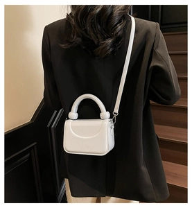 Détail du mini sac blanc avec un nœud à double boule unique sur la poignée chic
