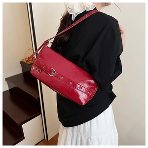 Detail showing red glossy leather shoulder bag with silver buckle and metallic eyelets