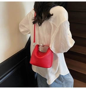 Detail view of red lychee grain leather crossbody bag with silver buckle and shoulder strap