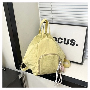 Détail du sac à dos en nylon texturé jaune clair avec breloque et poche zippée