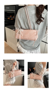 Détail du sac à bandoulière rose clair avec bordure en dentelle blanche et nœud perlé