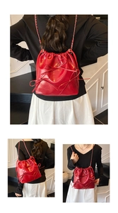 Detail view of red glossy leather bucket bag featuring three 3D bows and chain strap