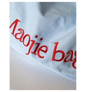 Vue détaillée du tissu en toile bleu clair avec broderie rouge Taojie bag sur le sac