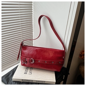 Detail of red rectangular underarm bag in glossy wrinkled patent leather with buckle