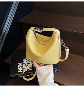 Detail of yellow litchi pattern leather bag with silver metal zippers on wooden steps