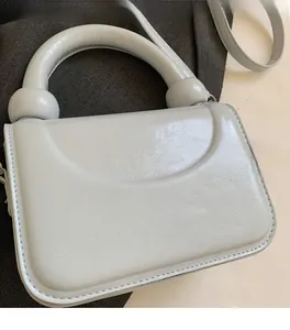 Détail du sac à main en cuir PU gris clair avec texture froissée et poignée sphérique