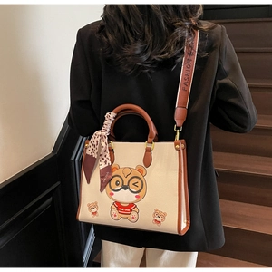 Detail of cream tote bag with bear print, leather handles, and leopard silk scarf wrap