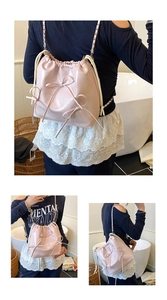 Detailed view of a pink drawstring bucket bag featuring decorative 3D bows and chain strap