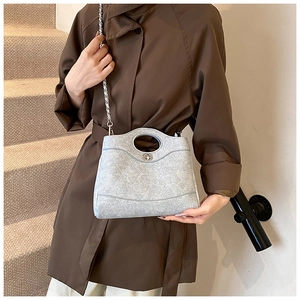 Sac seau matelassé gris clair avec bandoulière chaîne porté par un mannequin