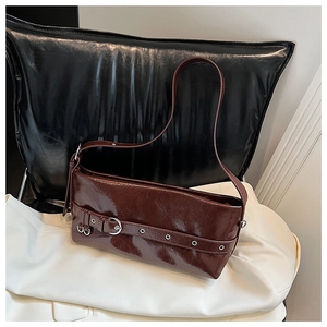 Detail of burgundy patent leather baguette bag featuring silver eyelet belt decoration