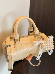 Chic off-white cylinder handbag in pleated patent leather with pearl and lace bow details