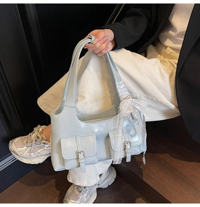 Dettaglio borsa tote azzurra con fibbie in metallo e nastro decorativo in pizzo bianco