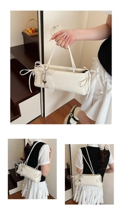 Détail du sac crème avec rubans latéraux, bordure en dentelle et pendentif perle en cœur