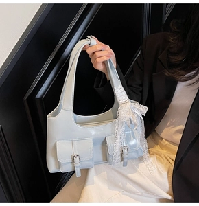 Dettaglio borsa tote azzurra metallizzata con fibbie sulle tasche e fiocco in pizzo