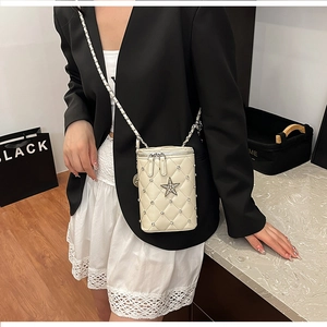 Detail of cream quilted cylindrical mini bag with rhinestone accents and star pendant