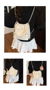 Detail showing versatile wearing styles of cream white drawstring bucket bag with bows