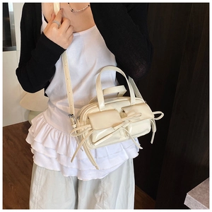 Détail du sac bowling en cuir blanc crème avec poches cargo et nœuds en ruban décoratifs