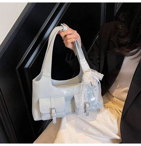 Dettaglio della borsa tote in pelle azzurra con fibbie d'argento e fiocco in pizzo