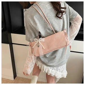 Gros plan du sac sous le bras rose avec nœud en dentelle, perles et cœur suspendu
