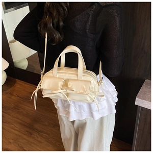 Détail du sac baguette blanc cassé avec poches avant et accents de rubans élégants