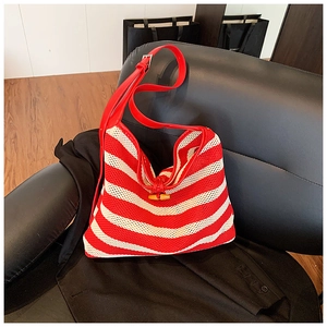 Detail view of red striped knit tote bag featuring a wooden horn button and leather strap