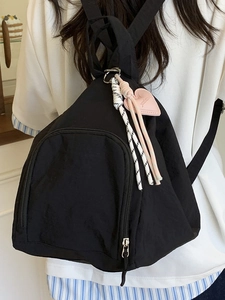 Mini sac à dos minimaliste en nylon noir avec pendentif cœur rose porté par un mannequin
