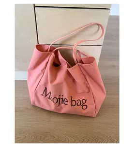 Vue détaillée de la broderie sur le grand sac cabas en toile rose corail avec bandoulière