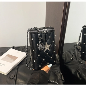 Detailed close-up of quilted black bucket bag with silver studs and star pendant