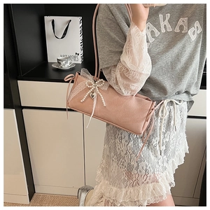 Détail du sac à bandoulière rose en simili cuir avec dentelle blanche et nœud perlé