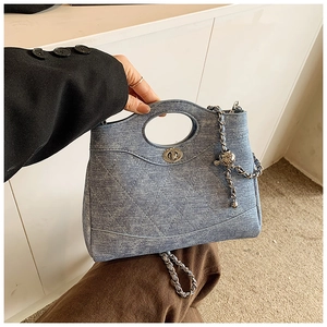 Détail du sac seau en denim matelassé bleu avec chaîne dorée et boule métallique