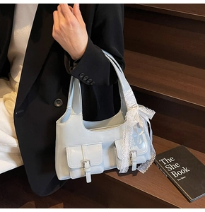 Dettaglio della borsa sottobraccio celeste con due tasche frontali e nastri di pizzo bianco