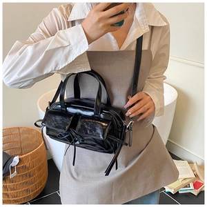 Détail d'un sac bowling en cuir verni noir avec poches avant et décoration de nœud